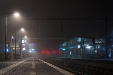 Fototapeta na wymiar Foggy night at a modern railway platform in a city.