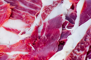 Portions of ham on wooden tray on white background