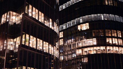 Pattern of office buildings windows illuminated at night. Lighting with Glass architecture facade design with reflection in urban city.