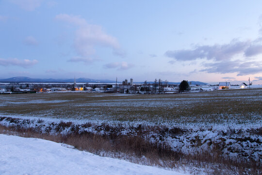 Rural blue hour morning winter landscape with small village and snowy fields along the route 281, Saint-Michel-de-Bellechasse, Quebec, Canada, Quebec, Canada