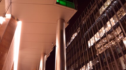 Pattern of office buildings windows illuminated at night. Lighting with Glass architecture facade design with reflection in urban city.