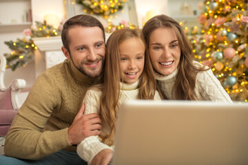 Young family sitting looking excited while having a video call