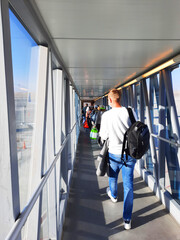 Passengers go along the telescopic gangway to board the plane.