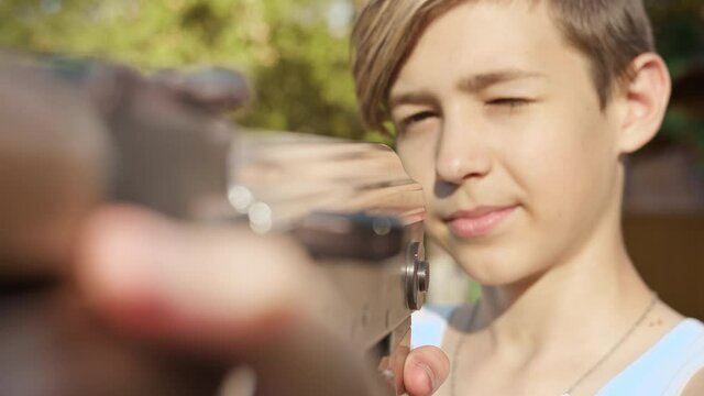portrait of a serious boy reloading a kalashnikov assault rifle outdoors, children's games