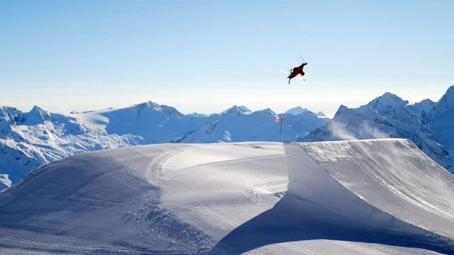 Freestyle skiing in a fun park on a big ski jump. Skiing on a very big jump in ultra slomotion. Freeride skiing awesome ski trick on a big ski jump. Freestyle skier in slomotion.