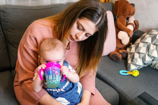 Mom Gives Baby Drink From Sippy Cup, Maternal Care Concept, Lifestyle