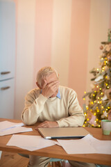 Elderly man sitting at the table and feeling tired