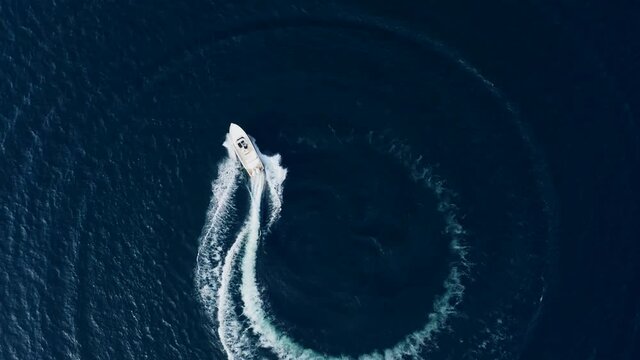 Aerial Top Down View of Speed Boat Circling Around on Iseo Lake, Italy.
Drone View of Luxury Boat doing Donuts Circles on Bue Water Lake.