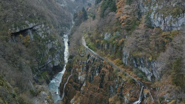 Top Down Aerial Drone View of Water Stream Flowing Along Rocky Ravine in Mountain Woods. High View of Waterfalls. Autumn Warm Colors.
