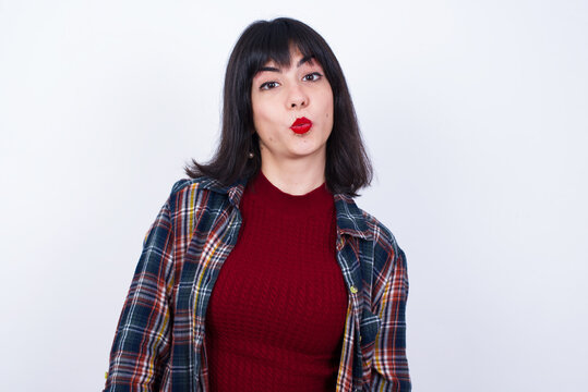 Young beautiful Caucasian woman wearing plaid shirt against white wall, expressing disgust, unwillingness, disregard having tensive look frowning face, looking indignant with something.