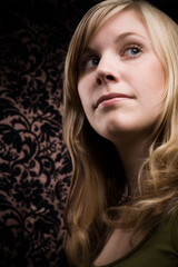 Fototapeta premium Young blonde girl looking up. Studio photo on dark background.