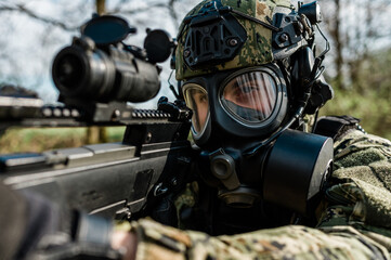 Fototapeta na wymiar Croatian soldier in Cropat woodland uniform wearing gas mask M95 and assault rifle G36.