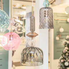A group of switched-off ceiling chandeliers with a transparent glass cover on the background of a...
