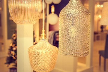A group of switched-off ceiling chandeliers with a transparent glass cover on the background of a...