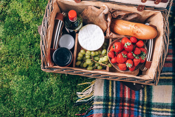 Picnic set with fruit, cheese, honey, strawberries, grapes, baguette, wine, wicker basket for...