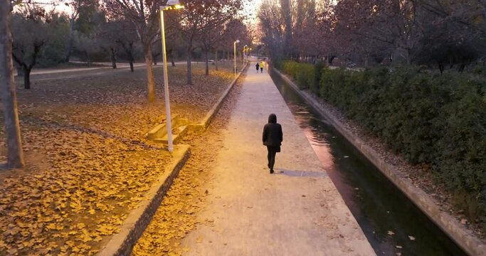 vista a&eacute;rea desde dron de mujer paseando anochecer en parque oto&ntilde;al