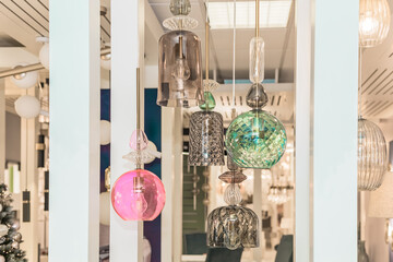 A group of switched-off multicolored lamps with a gray, turquoise, pink glass ceiling is suspended...