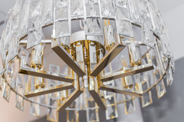 Close up of one turned off luxury expensive chandelier from a transparent crystal ceiling lampshade. Classic style in a modern interior. Inside. White light.