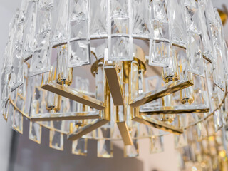 Close up of one turned off expensive chandelier from a transparent crystal ceiling lampshade....