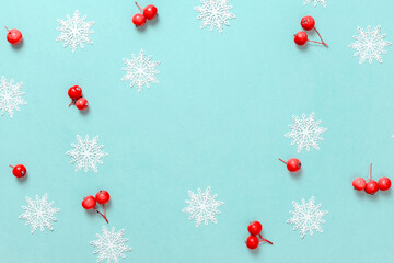 Holiday winter background. White snowflakes, red berry in Christmas composition on pastel blue background for greeting card. Xmas backdrop with space for text.