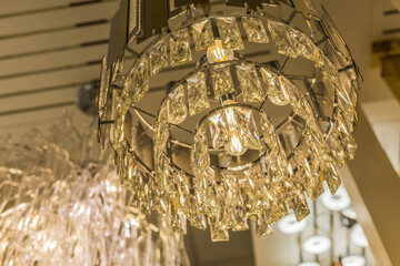 Close up of one luminous luxury expensive chandelier from a transparent crystal ceiling lampshade....