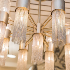 Close up of a group ceiling luxury expensive chandelier made of chains. Unique style in a classic interior. Indoors. Warm yellow light.