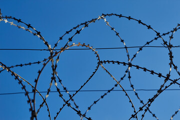 Round barbed wire against a clear sky, close-up