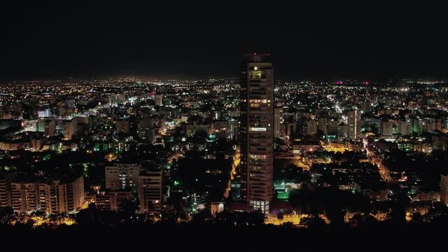 Flight in elevation in the city of Santo Domingo in front of La Torre Canei, and in the background the great illuminated city, rays in the sky, taken with drone