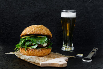 Burger and beer in a glass on a dark background. Hamburger