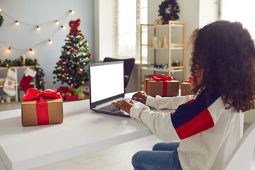 Girl video calling Santa or relatives or studying using laptop with blank copy space screen