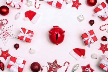 Red piggy bank surrounded by Christmas gifts and decorations on a white background.