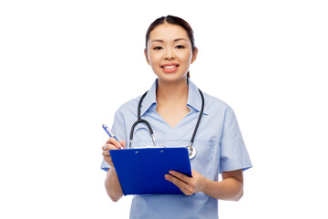 medicine, profession and healthcare concept - happy smiling asian female doctor or nurse in blue uniform with clipboard and pen over white background