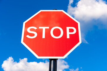 Red stop traffic street sign on blue sky background
