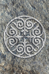 Ornamental print on the stone surface. Vintage ornament on the stone. Embossed drawing. Close-up. Stone texture. Pattern on the stone. Embossed pattern. Wallpaper. Tile