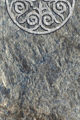 Ornamental print on the stone surface. Vintage ornament on the stone. Embossed drawing. Close-up. Stone texture. Pattern on the stone. Embossed pattern. Wallpaper. Tile