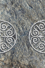 Ornamental print on the stone surface. Vintage ornament on the stone. Embossed drawing. Close-up. Stone texture. Pattern on the stone. Embossed pattern. Wallpaper. Tile