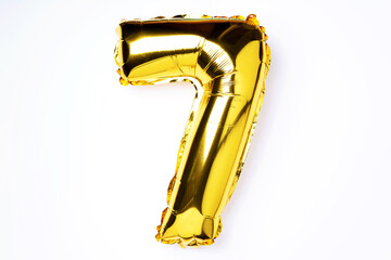 Creative layout. Golden foil balloon number and digit seven 7. Birthday greeting card. Anniversary concept. Top view. Copy space. Stylish gold numeral over white background. Numerical digit.