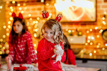Portrait of a girl in Christmas pyjamas holding rat in the kitchen with lights.