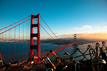 Photo of Golden Gate bridge at sunset with a fence covered in locks.