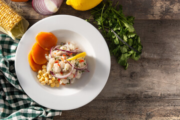 Traditional peruvian ceviche with fish, sweet potato, corn and vegetables on wooden table.  Top view. Copy space