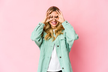 Young caucasian blonde woman showing okay sign over eyes