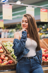 A girl in a supermarket buys apples