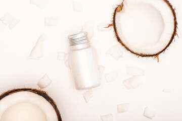 top view of coconut halves and flakes near bottle with homemade lotion on white, stock image