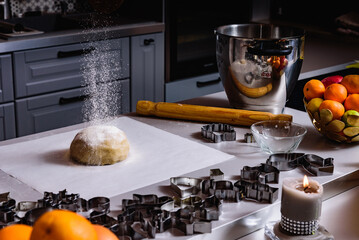 Steps of making Christmas cookies. Home kitchen with gray table. Ginger dough for gingerbread, gingerbread men, stars, Christmas trees, rolling pin, spices (cinnamon and anise)