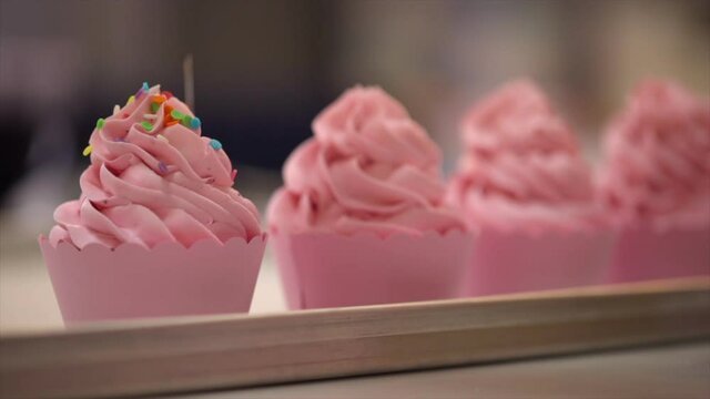 Decorating Cupcake With Sprinkles In Bakery. Woman Putting Sprinkles On Muffin
