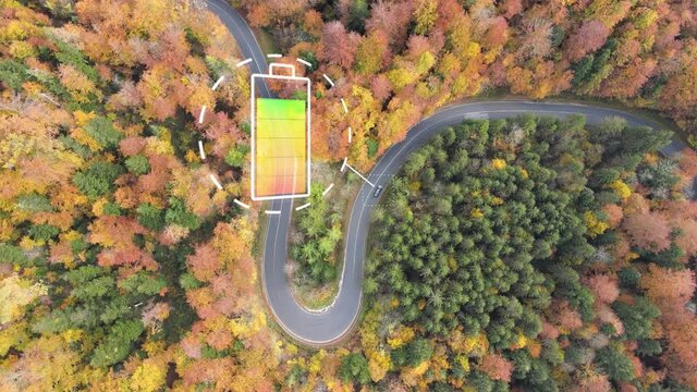Concept electric car on curved road amidst autumn trees with animation of draining battery indicator. Aerial top down.