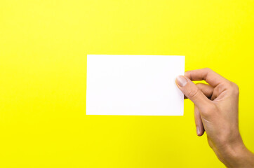 White card in a female hand on a yellow background