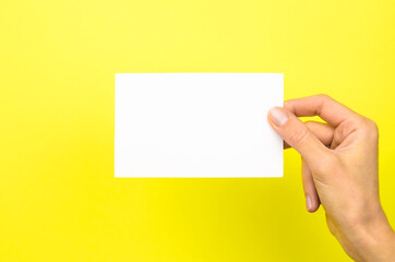 White card in a female hand on a yellow background