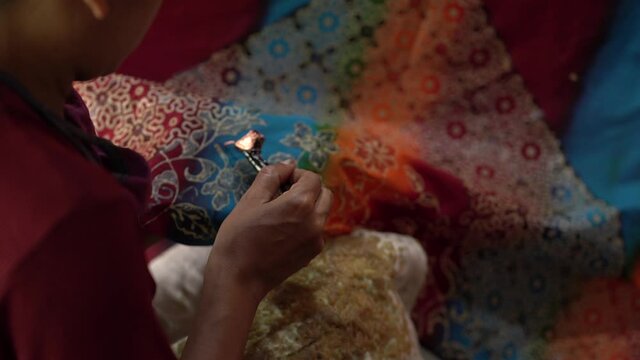 close up, women make batik fabrics in a traditional, flexible way.