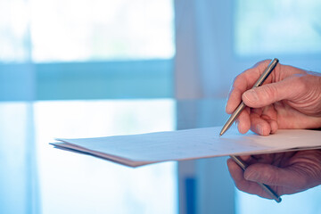 Man signs a document form with a ballpoint pen in the office